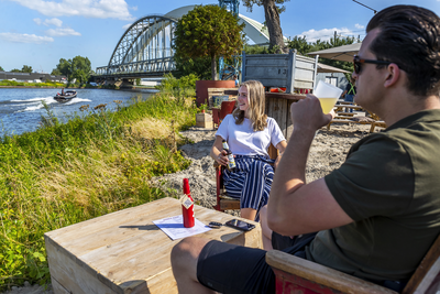 903780 Afbeelding van twee bezoekers van het Stadsstrand DUS aan de Sophialaan te Utrecht, met op de achtergrond het ...